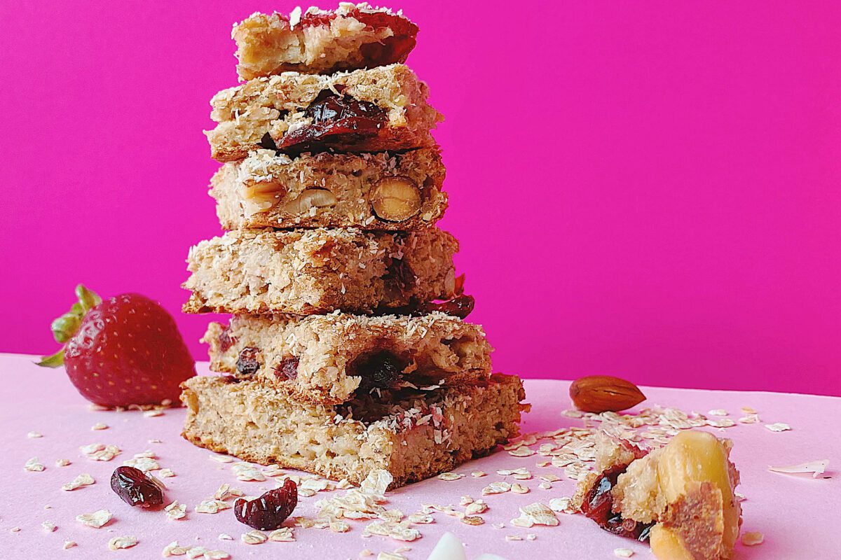 A stack of granola oatmeal bars on a pink background.