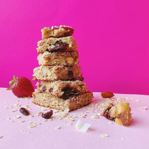 A stack of granola oatmeal bars on a pink background.