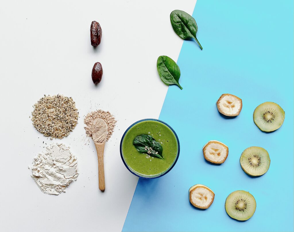 A captivating image captures the eye: a tall glass, brimming with a lush green smoothie, stands proudly on a table. Crafted with fresh ingredients like ginseng, kiwifruit, dates, and chia seeds, it's a sight to behold. A sprinkle of chia seeds and a slice of kiwifruit elegantly garnish the rim.