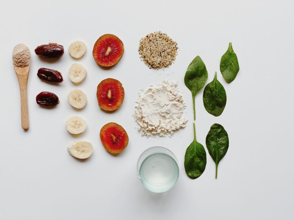 Recipe ingredients for green smoothie with ginseng, hemp seeds, coconut water, dates, spinach and kiwifruit.