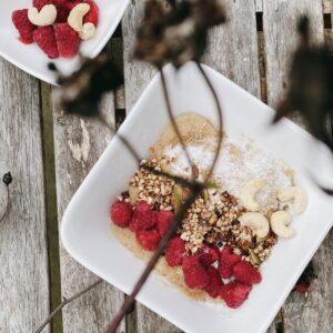 An image of a beautifully arranged bowl filled with cooked amaranth grains topped with a generous serving of fresh, vibrant raspberries. The bowl is placed on a rustic wooden table, creating a visually appealing and appetizing scene. The combination of the nutritious amaranth and juicy raspberries showcases a wholesome and delicious breakfast or snack option. The image captures the essence of healthy eating and natural ingredients, making it an excellent choice for promoting the benefits of this superfood dish.