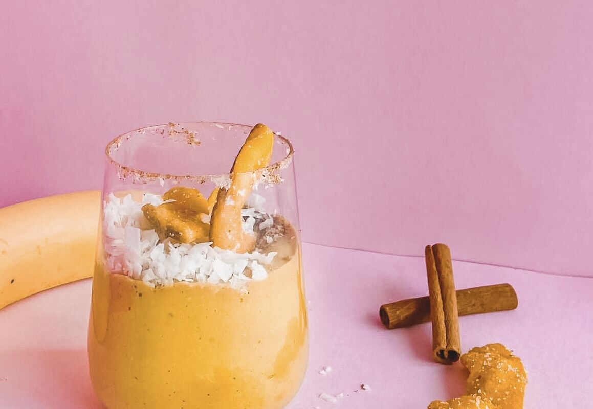 A banana and maca smoothie with cinnamon and coconut on a pink background.