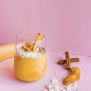 A banana and maca smoothie with cinnamon and coconut on a pink background.