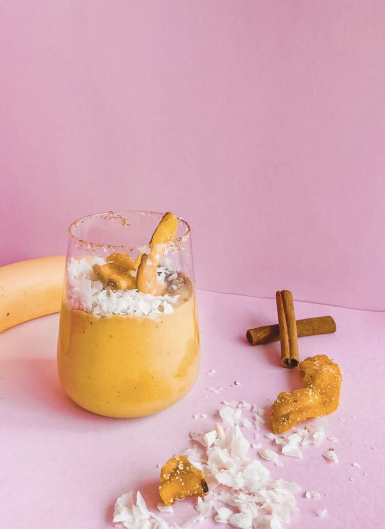 A banana and maca smoothie with cinnamon and coconut on a pink background.